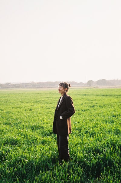 穿着黑色长袖衬衫的女人白天站在绿草地上